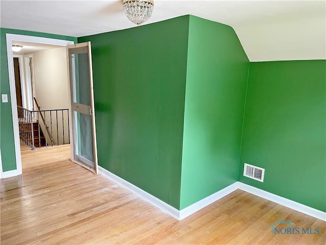 interior space with visible vents, baseboards, vaulted ceiling, and wood finished floors