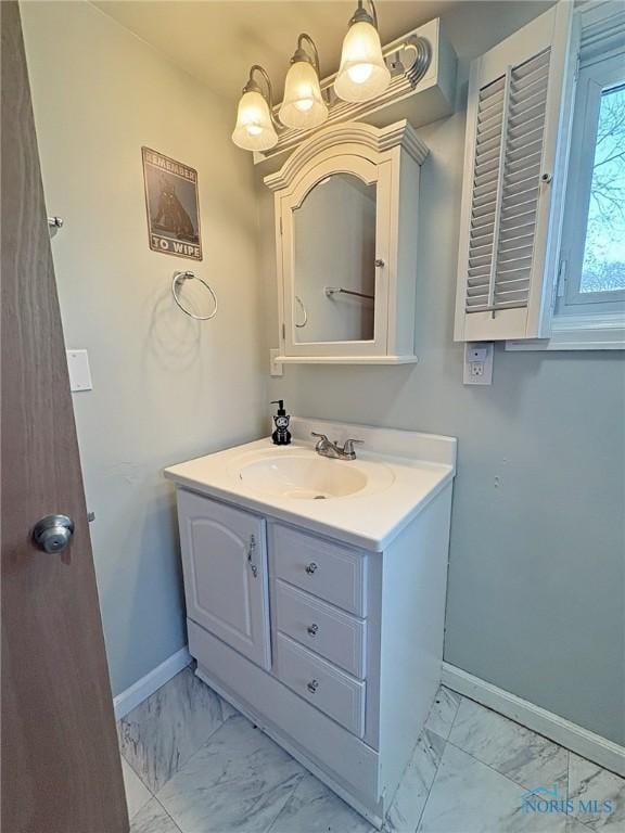 bathroom with a chandelier, vanity, marble finish floor, and baseboards