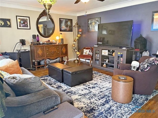 living room featuring ceiling fan, baseboards, ornamental molding, and wood finished floors
