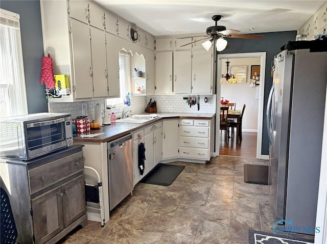 kitchen with a sink, appliances with stainless steel finishes, a ceiling fan, backsplash, and a toaster