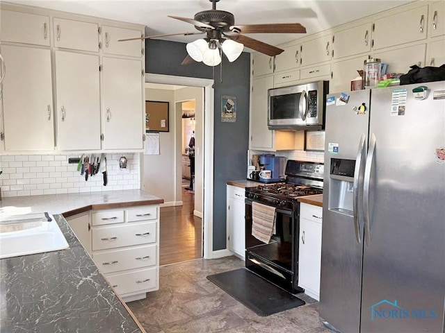kitchen featuring a sink, a ceiling fan, white cabinetry, stainless steel appliances, and decorative backsplash