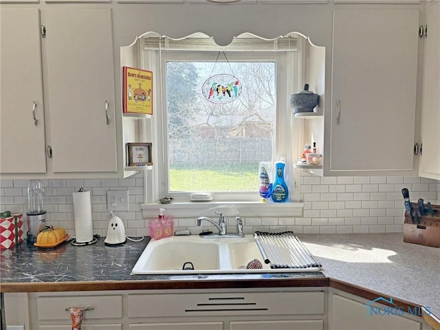 kitchen with tasteful backsplash, white cabinets, open shelves, and a sink