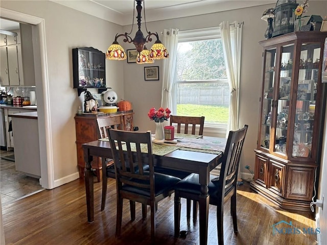 dining area featuring an inviting chandelier, baseboards, and dark wood finished floors