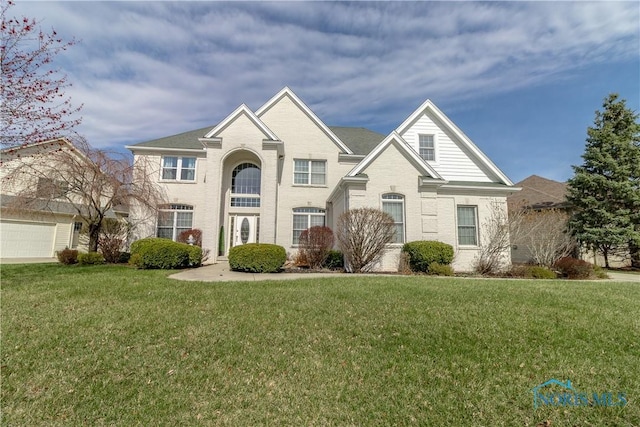 view of front of property featuring brick siding, a front yard, and an attached garage