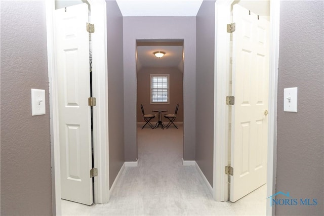 hallway featuring baseboards and a textured wall