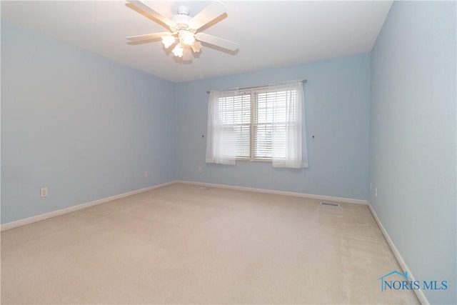 spare room featuring baseboards, ceiling fan, visible vents, and light colored carpet