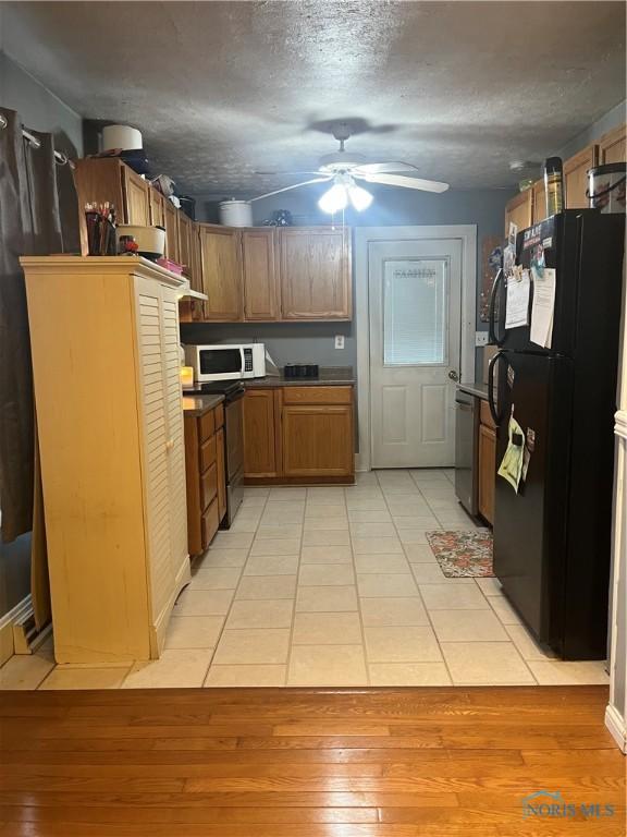 kitchen featuring freestanding refrigerator, stainless steel dishwasher, brown cabinets, ceiling fan, and white microwave