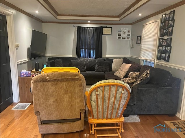 living room featuring visible vents, a tray ceiling, and wood finished floors