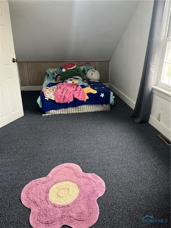 bedroom featuring baseboards, carpet flooring, vaulted ceiling, and wooden walls