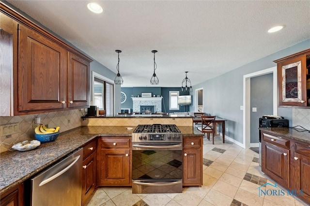 7106 Country Creek Rd, Maumee, OH 43537 - kitchen with stainless steel appliances, a peninsula, decorative backsplash, a stone fireplace, and decorative light fixtures