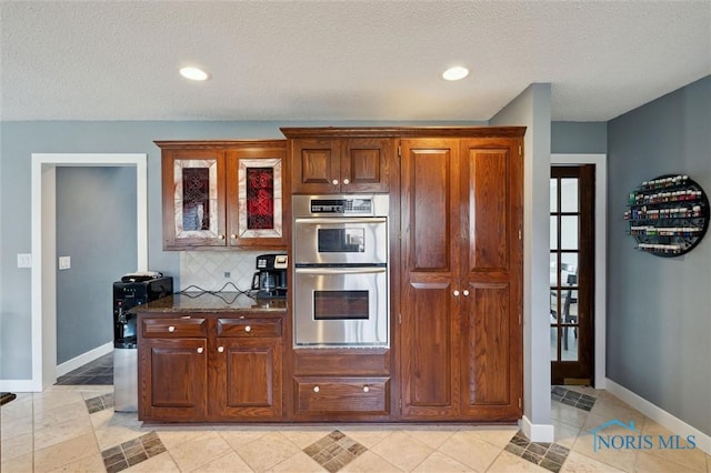 7106 Country Creek Rd, Maumee, OH 43537 - kitchen with stainless steel double oven, baseboards, backsplash, glass insert cabinets, and a textured ceiling