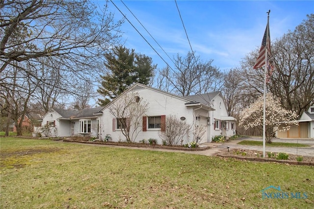 view of side of home with a lawn, a garage, and driveway
