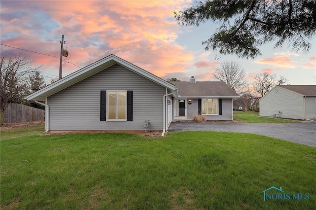 view of front facade featuring a front lawn, fence, and driveway
