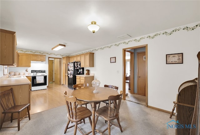 dining room featuring baseboards and light carpet