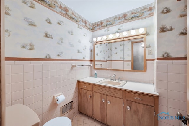 bathroom with vanity, wallpapered walls, a wainscoted wall, toilet, and visible vents