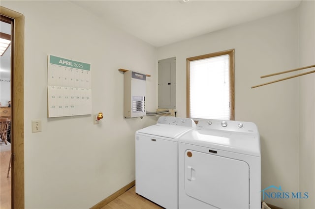 washroom featuring baseboards, electric panel, laundry area, light wood finished floors, and washing machine and clothes dryer
