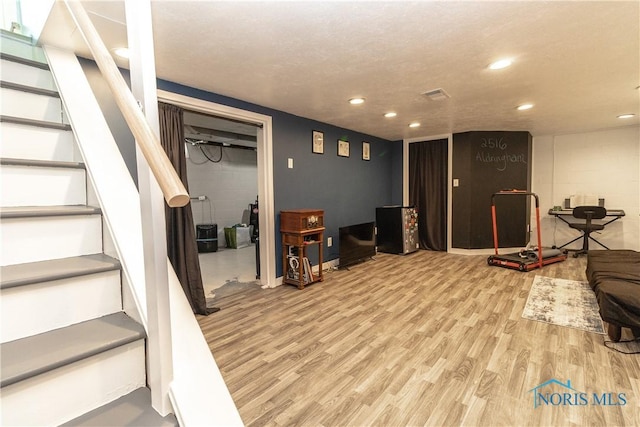 finished below grade area featuring concrete block wall, recessed lighting, wood finished floors, and stairs