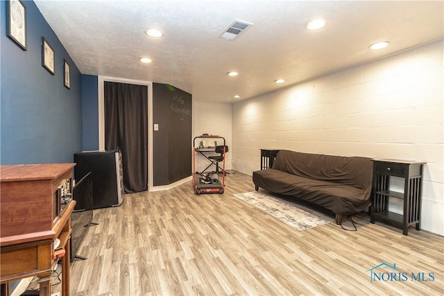 sitting room with light wood-style floors, recessed lighting, visible vents, and concrete block wall