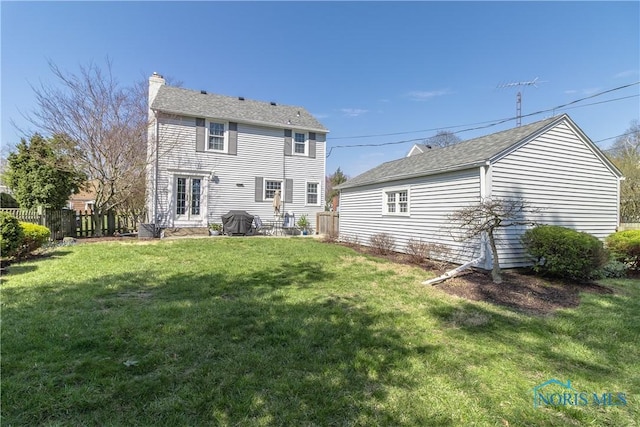 back of property with fence, a yard, and a chimney