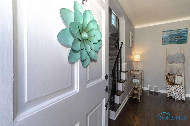foyer with stairs, visible vents, baseboards, and wood finished floors