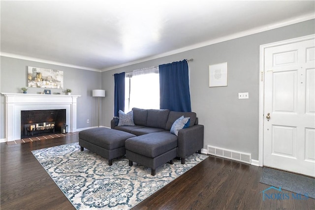 living room featuring a fireplace with flush hearth, wood finished floors, baseboards, and visible vents