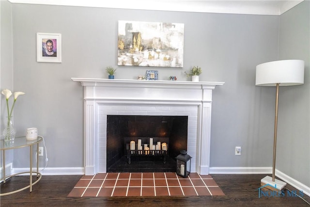 room details featuring a tile fireplace, baseboards, and wood finished floors