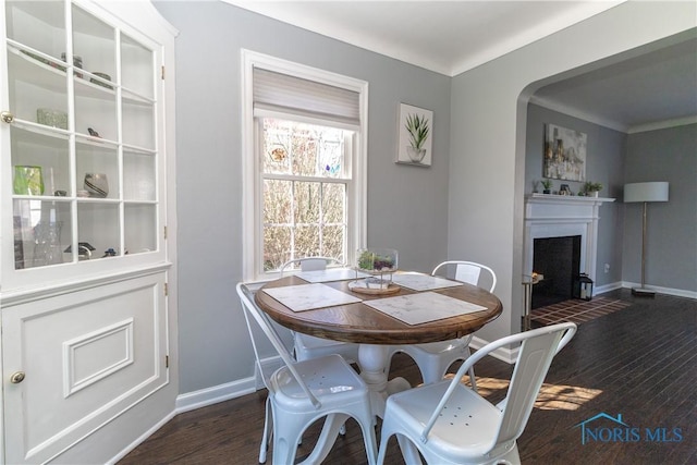 dining area with a fireplace with flush hearth, baseboards, and wood finished floors