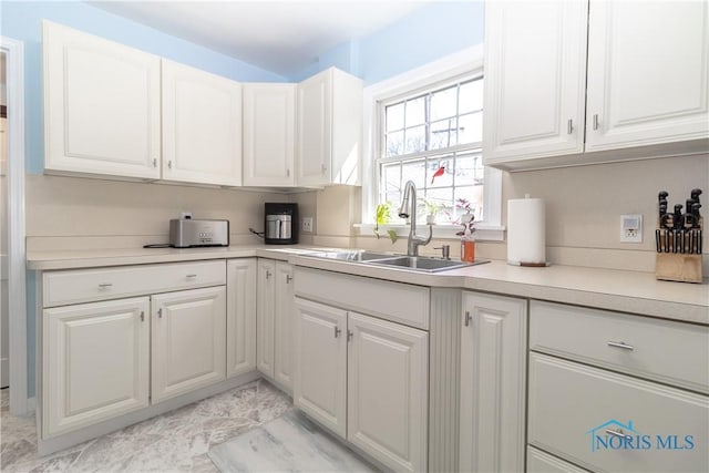 kitchen with a sink, light countertops, and white cabinetry