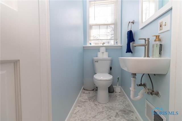 half bathroom with toilet, a sink, baseboards, and visible vents