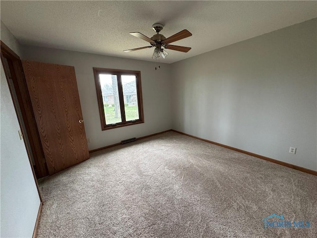 unfurnished bedroom featuring light colored carpet, baseboards, a ceiling fan, and a textured ceiling