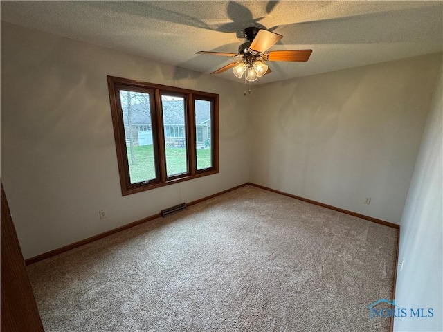 empty room featuring ceiling fan, carpet, baseboards, and a textured ceiling