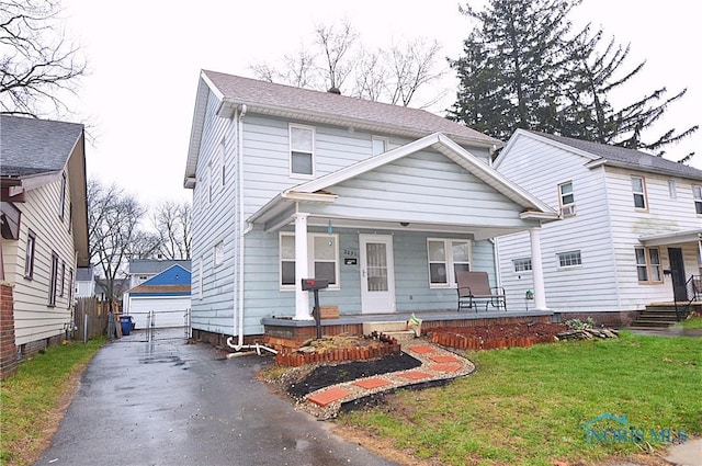 view of front facade featuring a front yard, a detached garage, an outdoor structure, and covered porch