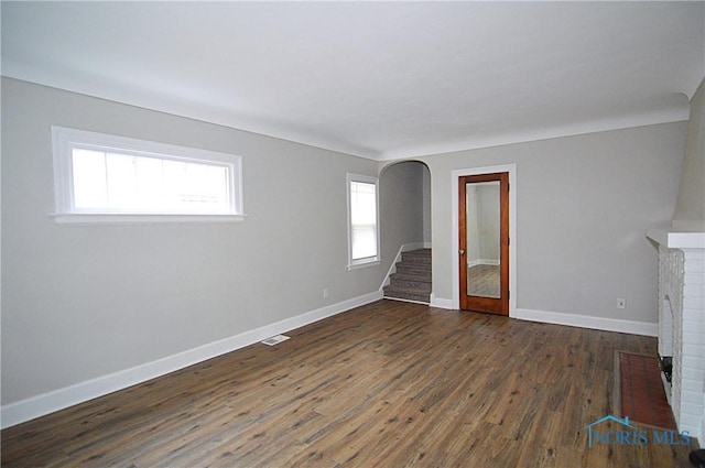 unfurnished living room with hardwood / wood-style floors, a fireplace, baseboards, and stairs