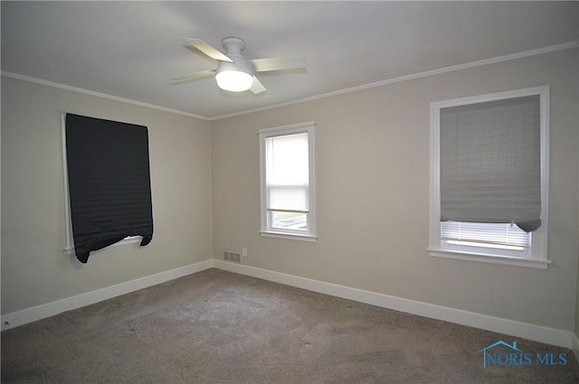 unfurnished room featuring crown molding, ceiling fan, visible vents, carpet floors, and baseboards