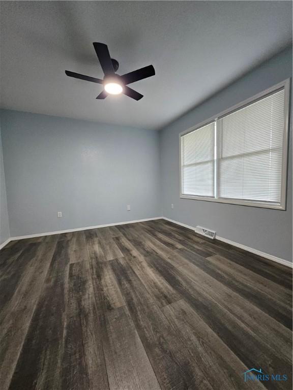 10308 Dowling Rd, Perrysburg, OH 43551 - spare room featuring dark wood-style flooring, ceiling fan, and baseboards