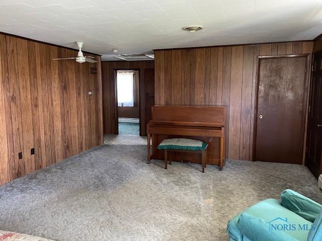 sitting room featuring wooden walls, visible vents, and carpet