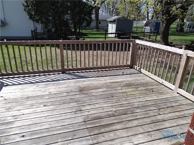 634 Cherry St, Wauseon, OH 43567 - wooden terrace with a lawn, a storage unit, and an outbuilding