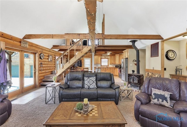 2525 N King Rd, Toledo, OH 43615 - living area featuring log walls, a wood stove, high vaulted ceiling, stairway, and plenty of natural light