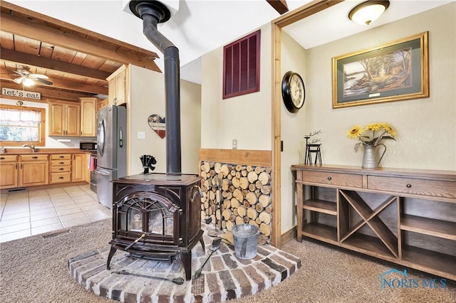 2525 N King Rd, Toledo, OH 43615 - living area featuring a wood stove, beamed ceiling, light carpet, and ceiling fan
