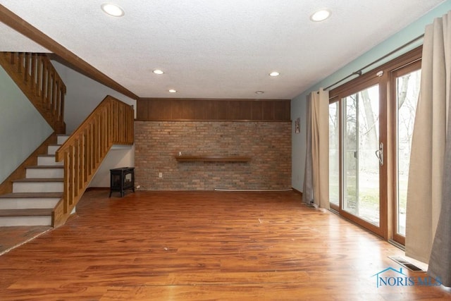 unfurnished living room featuring stairway, a healthy amount of sunlight, recessed lighting, and light wood-style flooring