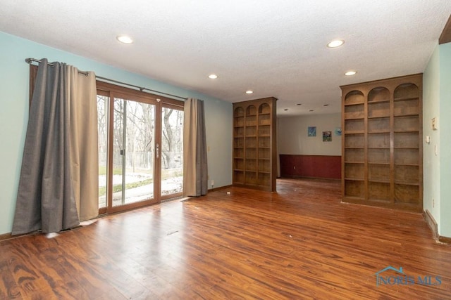 spare room with a textured ceiling, wood finished floors, recessed lighting, and baseboards