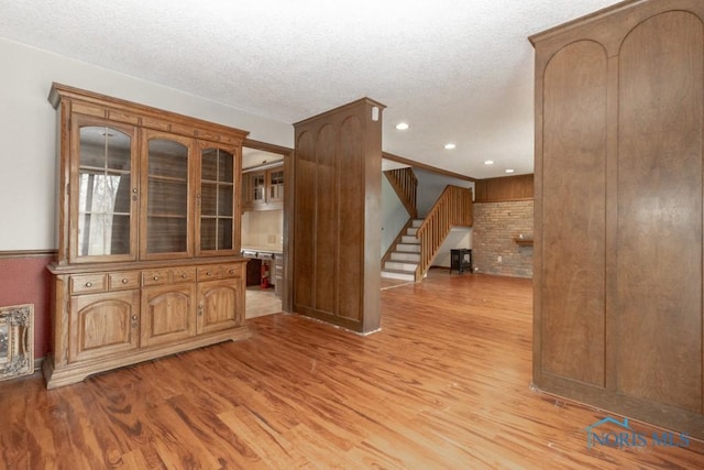 unfurnished room featuring stairs, a textured ceiling, and light wood-style flooring