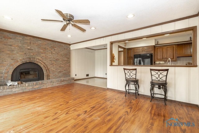 unfurnished living room with ornamental molding, ceiling fan, and a decorative wall