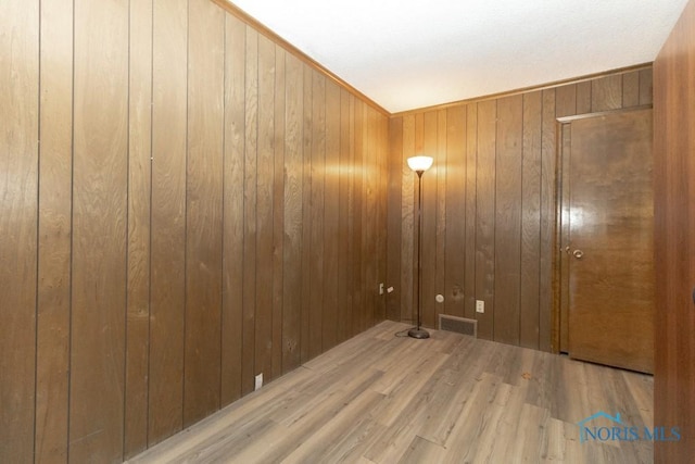 clothes washing area with visible vents, wood finished floors, and wooden walls