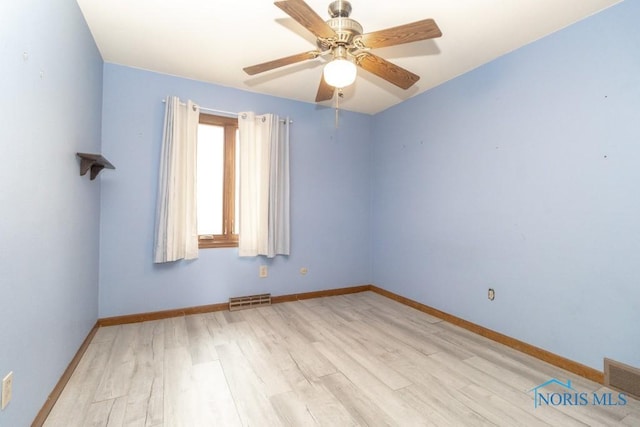 unfurnished room with a ceiling fan, visible vents, wood finished floors, and baseboards