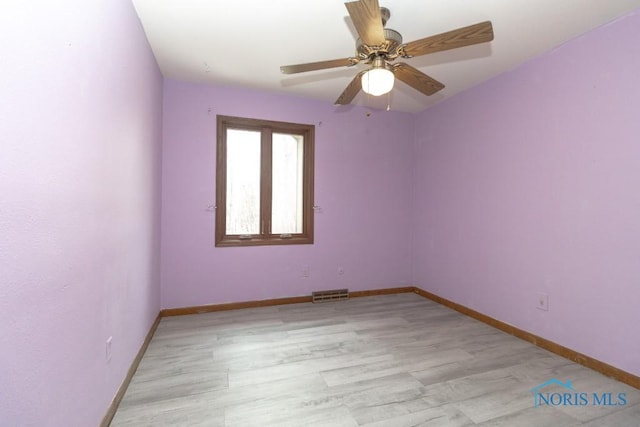 empty room featuring a ceiling fan, visible vents, baseboards, and light wood-style floors