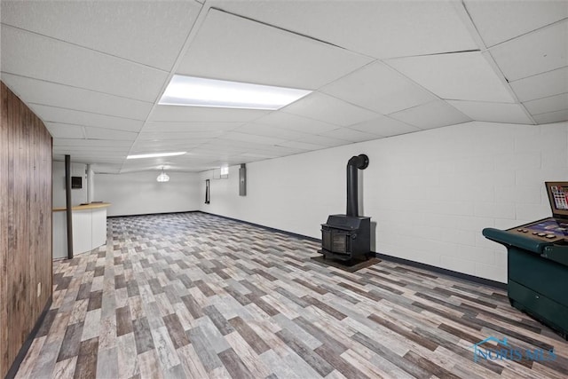 2560 Shoreland Ave, Toledo, OH 43611 - finished basement with wood finished floors, a wood stove, electric panel, concrete block wall, and a drop ceiling