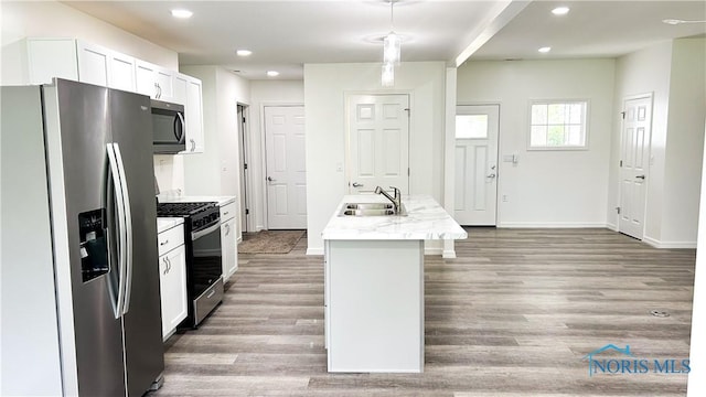 kitchen featuring stainless steel appliances, a sink, a kitchen island with sink, light wood finished floors, and baseboards