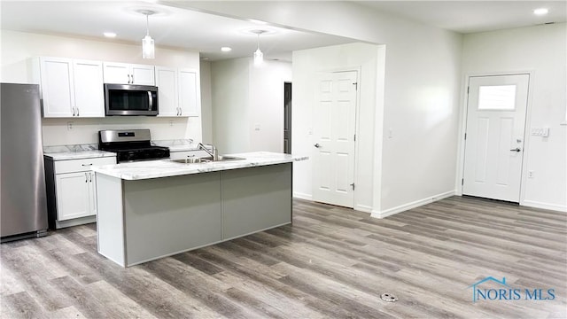 kitchen featuring stainless steel appliances, a sink, light wood finished floors, white cabinets, and recessed lighting