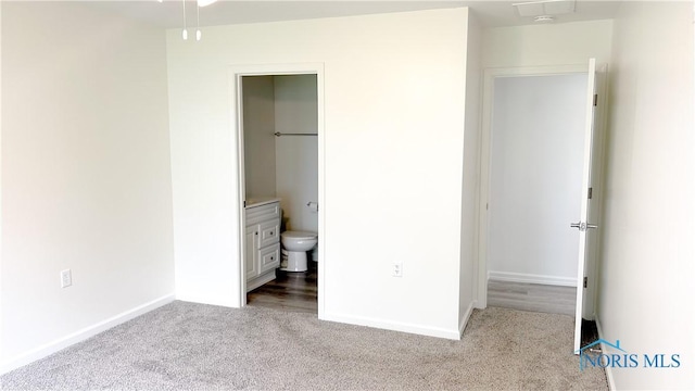 unfurnished bedroom with carpet flooring, baseboards, and ensuite bath